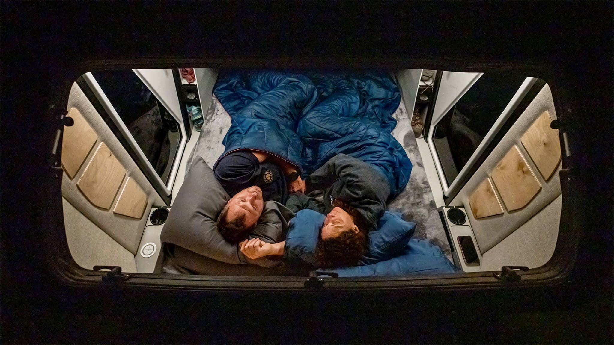 Two sleepers inside an Escapod TOPO2, as seen through the huge 2.5 x 5 ft stagazer window.