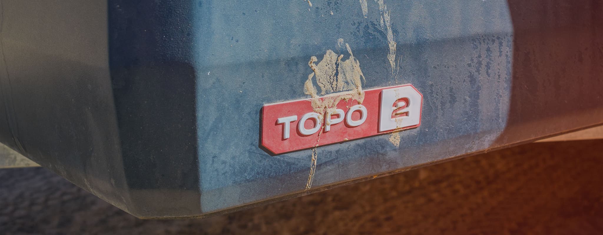 Close-up of the TOPO2 badge on a dusty Escapod trailer, showcasing its rugged and adventure-ready design.
