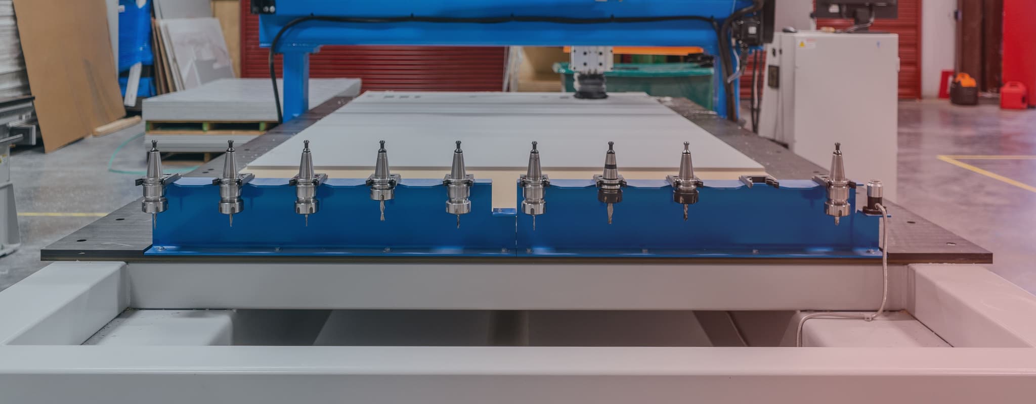 Close-up of a high-precision CNC machine in a workshop, featuring multiple drill heads and Escapod's industrial workspace in the background.