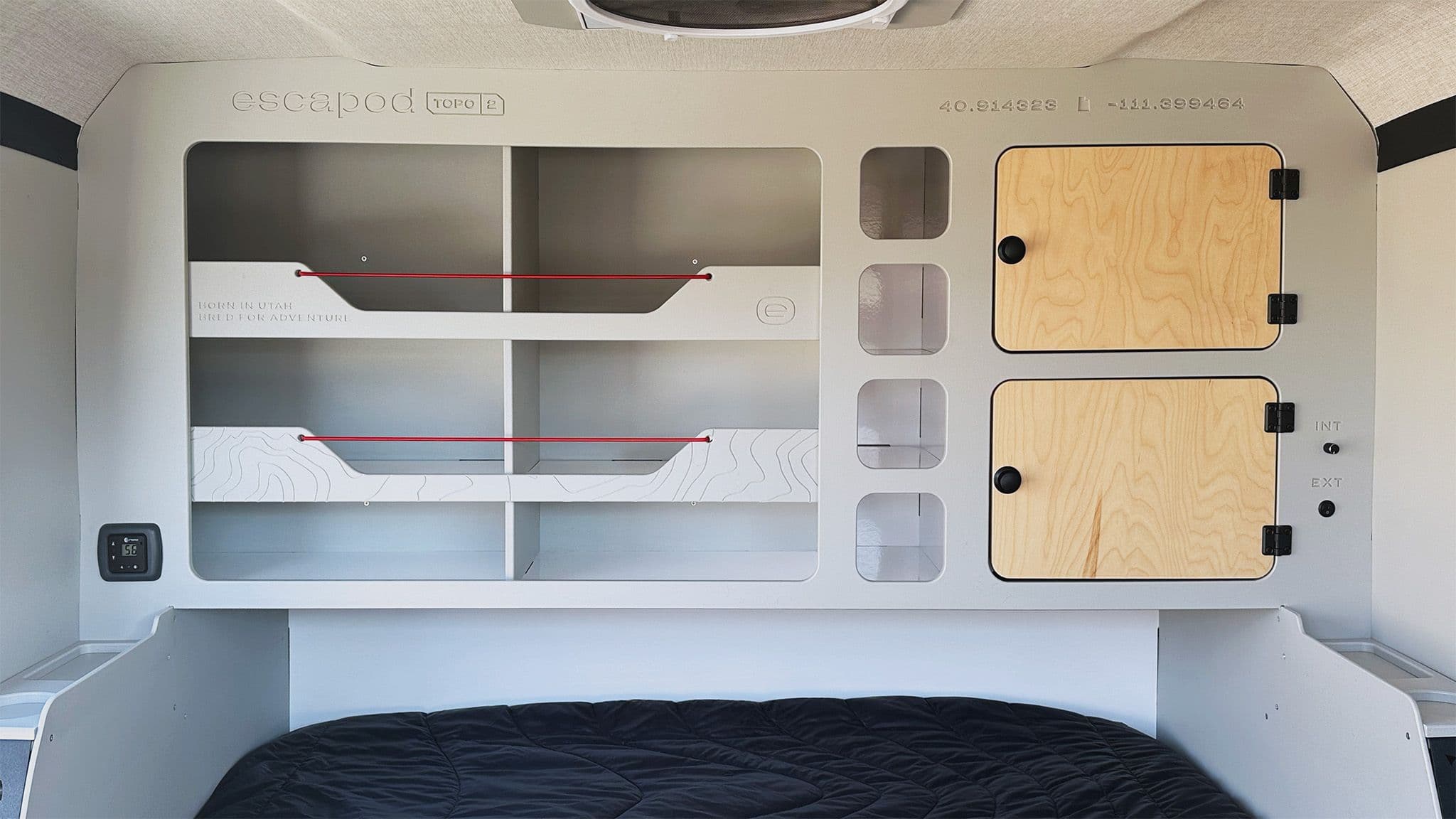 A wide shot of the interior of an Escapod TOPO2 Nomad, showing the cabinets and cubbies for storage of, two of which have baltic birch cabinet doors.
