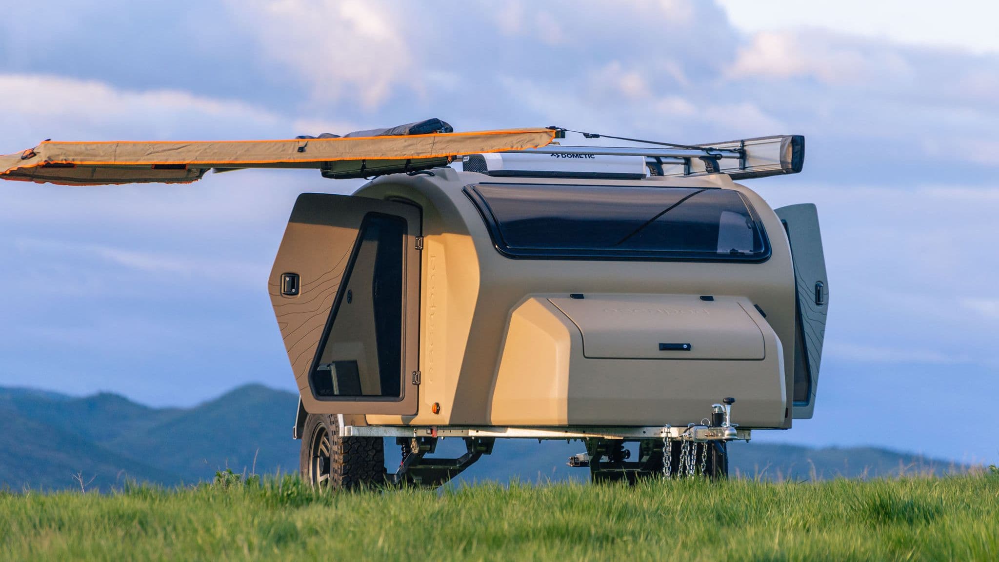 Side view of the Escapod TOPO2 trailer with an extended awning and panoramic window, designed for ultimate comfort while camping in the backcountry.