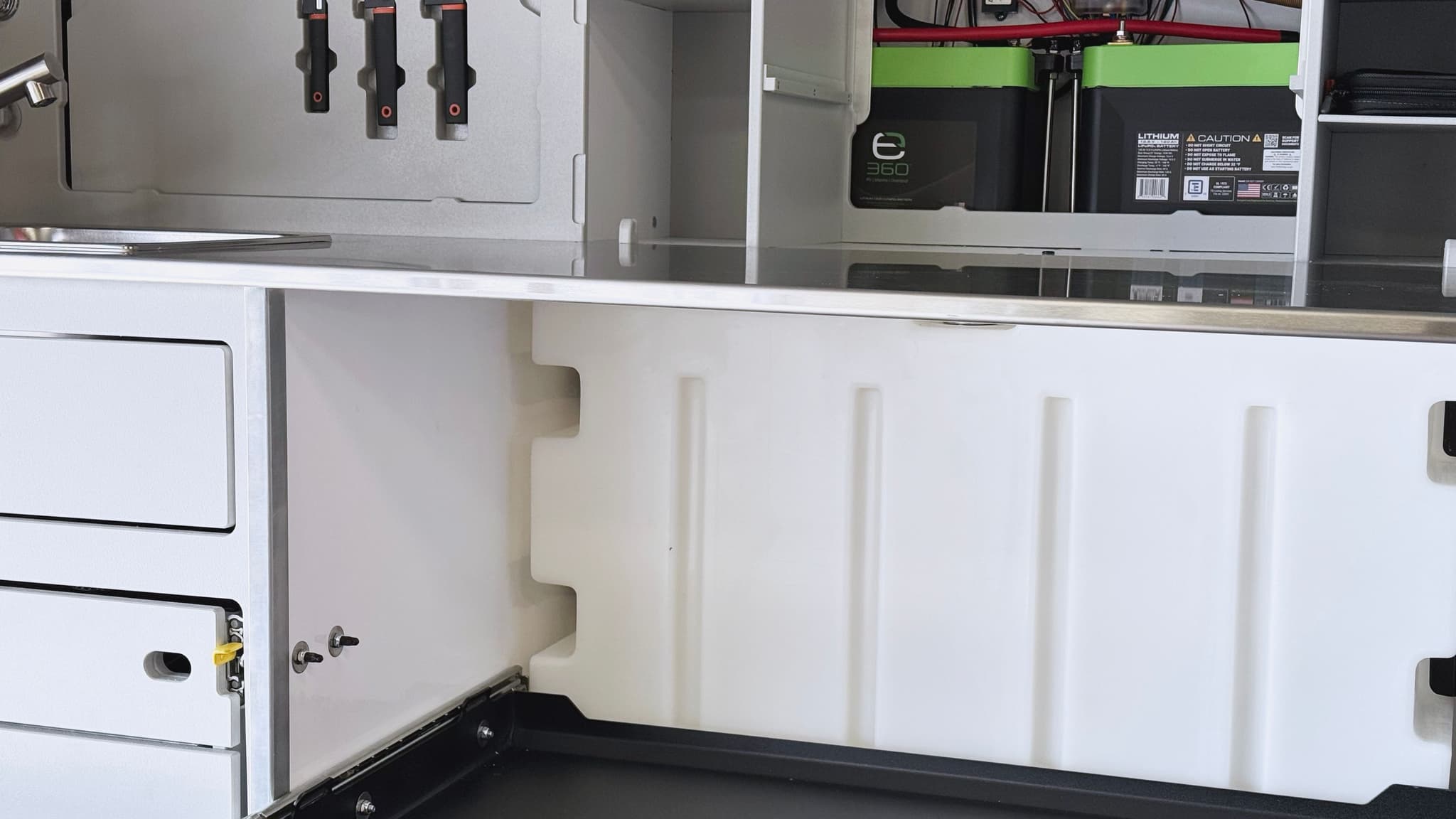 A detailed view of the galley of the Escapod TOPO2, with the 21 gallon water tank in the foreground, and the utilities closet and knife set visible in the background.