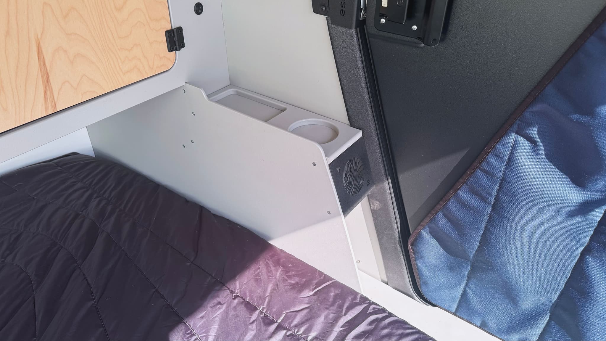 A detail show of the mudroom area of the Escapod TOPO2 Nomad, showing an area for shoes and a flat shelf on top for drinks and keys or wallet storage.