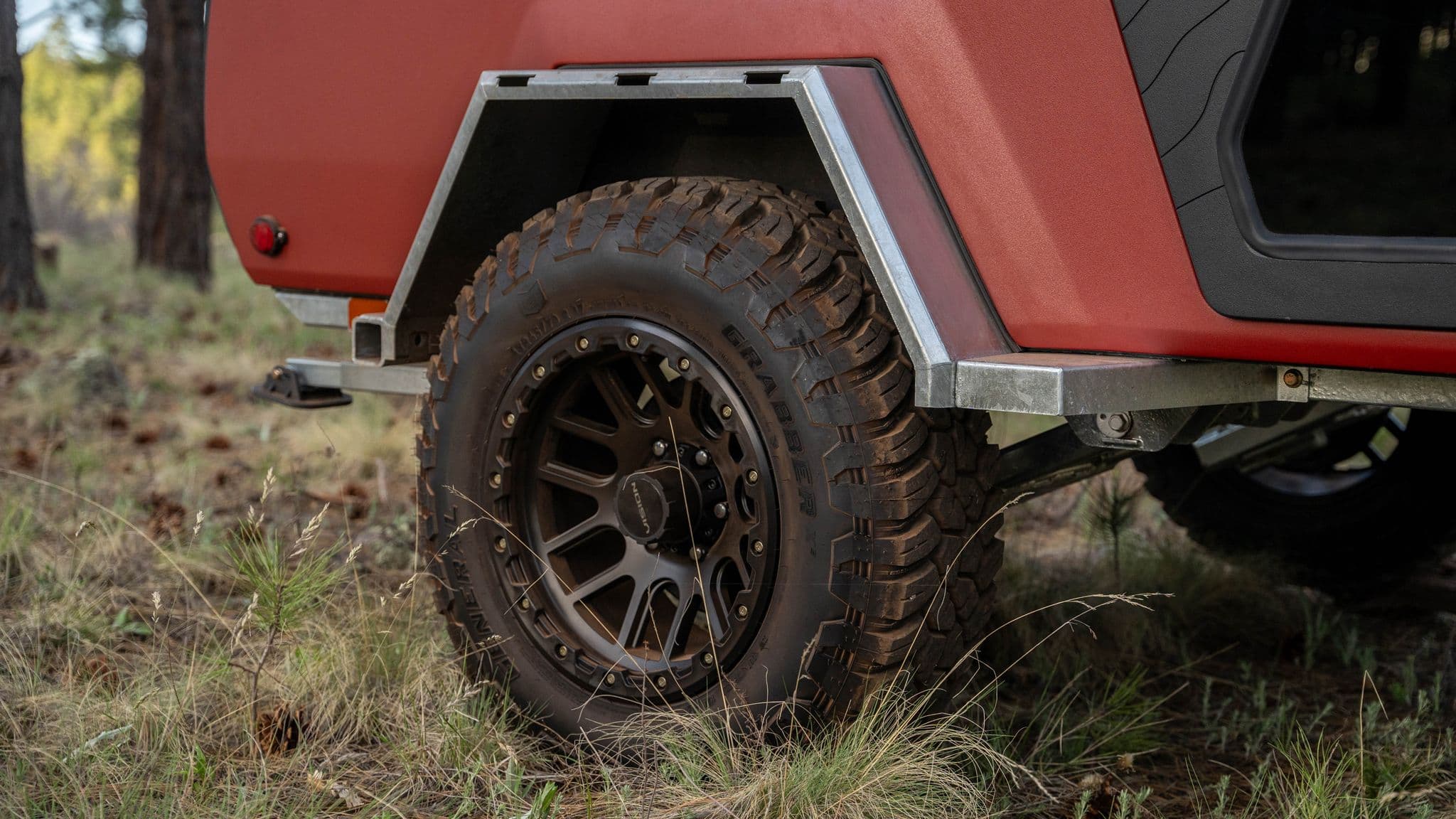 A close-up of the Escapod TOPO2βs off-road tire with deep treads, mounted under a sturdy metal fender.