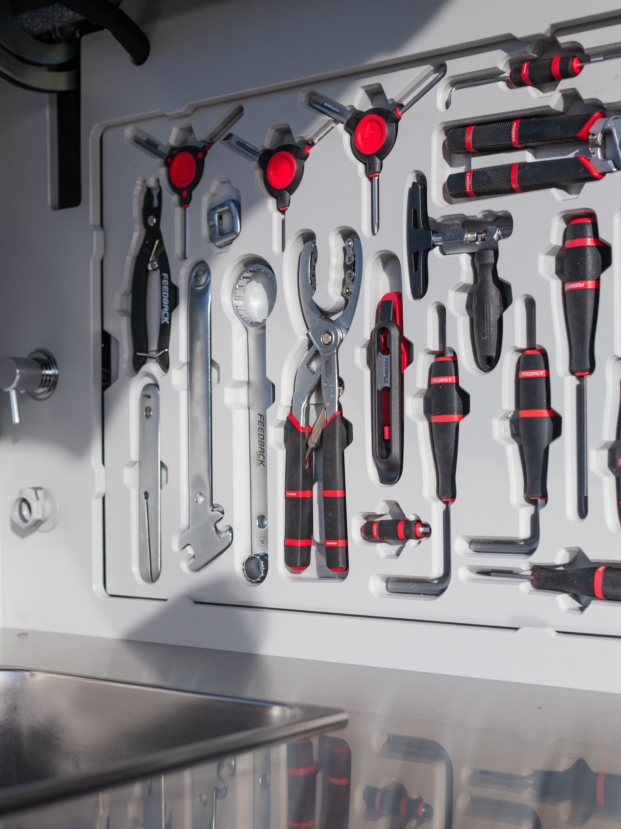 Close-up of the TOPO2 MTB galley tool board with pliers, wrenches, and screwdrivers mounted above a stainless sink and prep space.