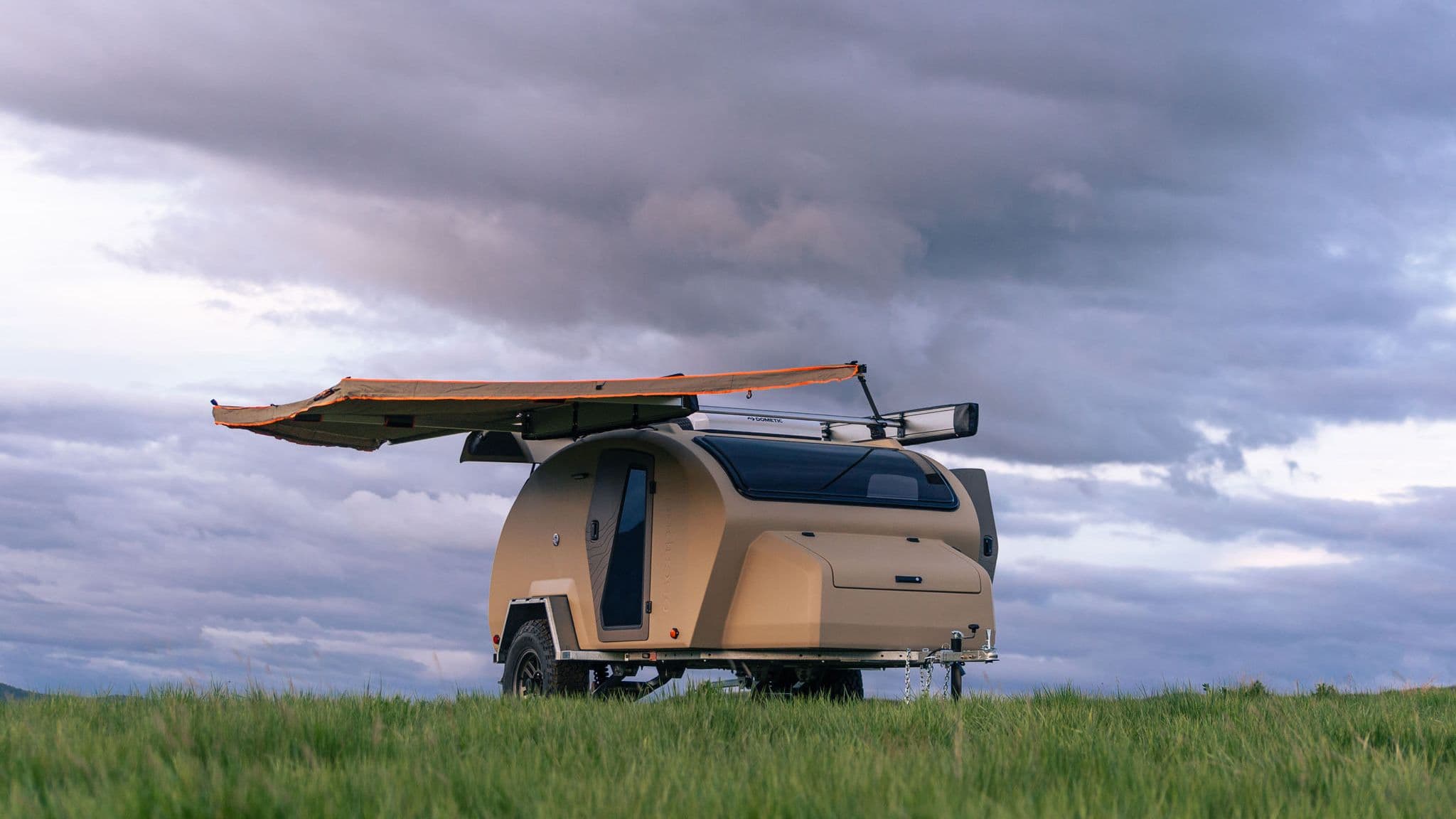 Escapod TOPO2 trailer under a dramatic cloudy sky with awning extended, built for rugged terrain, offering all-weather protection and off-grid comfort.